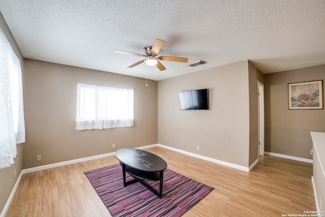 living area featuring ceiling fan, a textured ceiling, and light hardwood / wood-style flooring