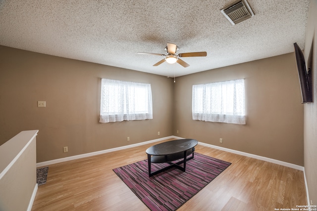 unfurnished room featuring light hardwood / wood-style floors, a textured ceiling, and ceiling fan