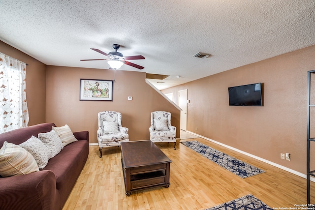 living room featuring light hardwood / wood-style flooring, a textured ceiling, and ceiling fan