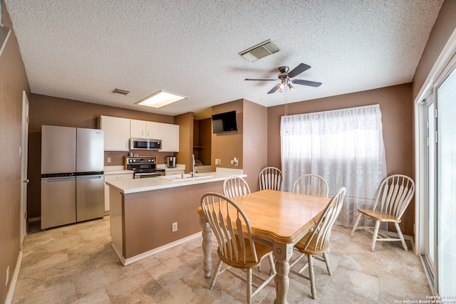 dining area with sink, light tile patterned floors, a textured ceiling, and ceiling fan