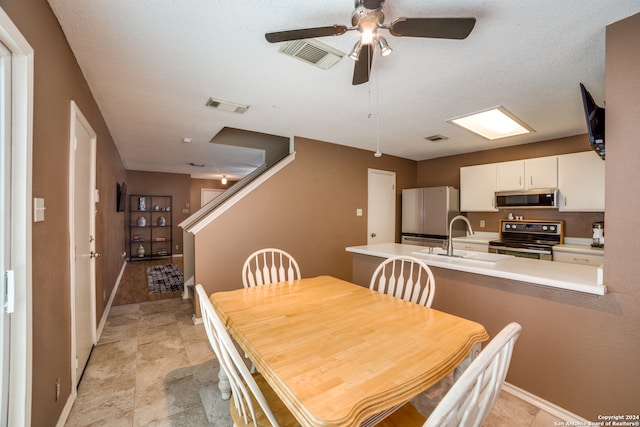 tiled dining area featuring sink, a textured ceiling, and ceiling fan