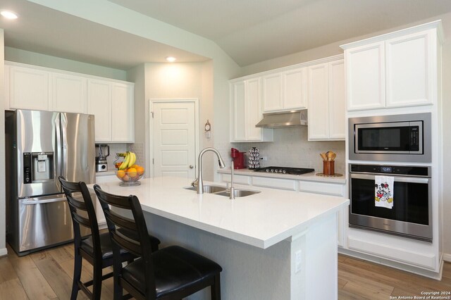 kitchen featuring white cabinetry, stainless steel appliances, tasteful backsplash, sink, and vaulted ceiling