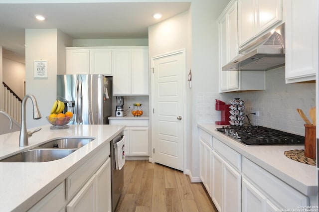 kitchen featuring sink, backsplash, white cabinets, light wood-type flooring, and stainless steel appliances