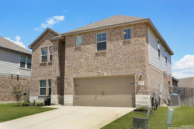 view of front facade with central air condition unit, a garage, and a front lawn