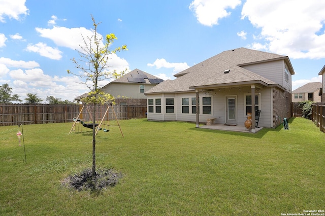 back of house featuring a patio, a playground, and a yard