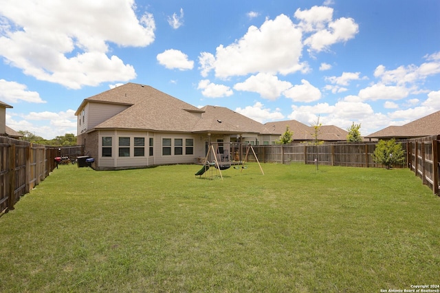 back of property featuring a playground and a yard