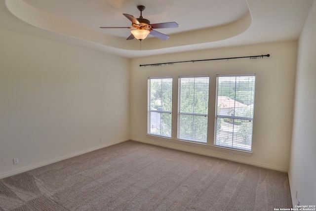 unfurnished room with ceiling fan, a raised ceiling, and carpet flooring