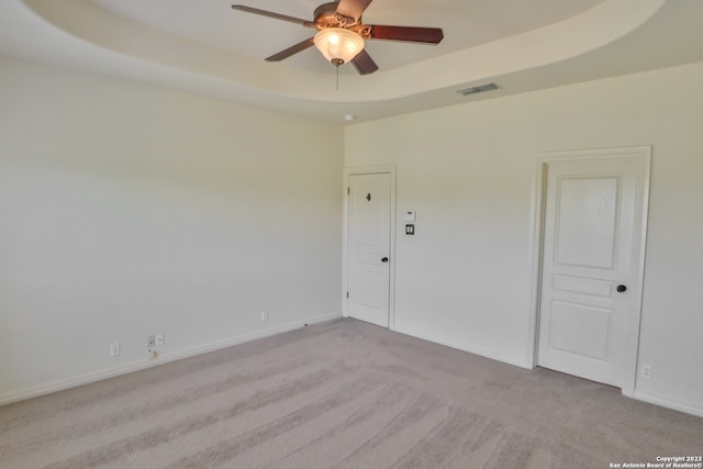 spare room featuring ceiling fan, a tray ceiling, and carpet flooring