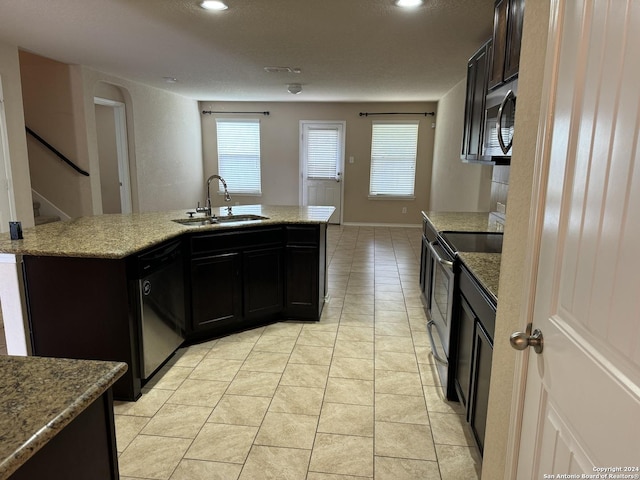 kitchen featuring dishwasher, an island with sink, range with electric stovetop, and sink