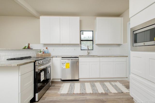 kitchen featuring appliances with stainless steel finishes, backsplash, sink, light hardwood / wood-style floors, and white cabinetry