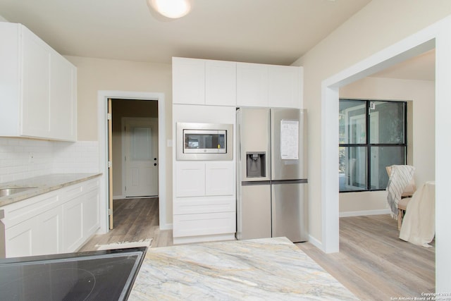 kitchen with decorative backsplash, light stone counters, white cabinetry, and stainless steel appliances