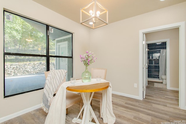 dining area with a wealth of natural light, light hardwood / wood-style flooring, and an inviting chandelier