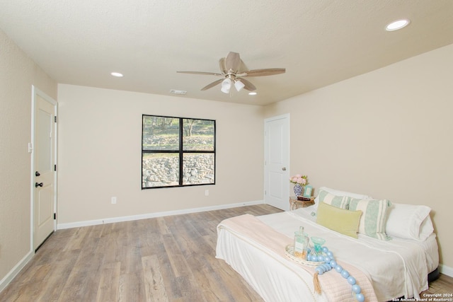 bedroom with a textured ceiling, light wood-type flooring, and ceiling fan