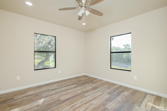 empty room featuring ceiling fan, a wealth of natural light, and light hardwood / wood-style flooring