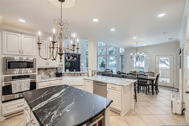 kitchen featuring a chandelier, a kitchen island, appliances with stainless steel finishes, decorative backsplash, and pendant lighting