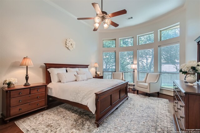 bedroom with dark wood-type flooring, multiple windows, ornamental molding, and ceiling fan