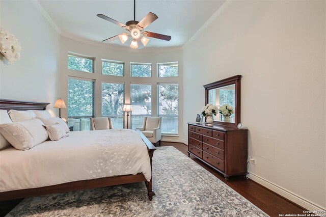 bedroom with a towering ceiling, dark hardwood / wood-style flooring, ornamental molding, and ceiling fan