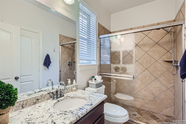 bathroom featuring vanity, walk in shower, and toilet