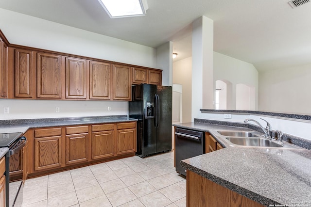 kitchen featuring sink, light tile patterned flooring, and black appliances