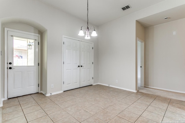 foyer entrance with an inviting chandelier and light tile patterned flooring