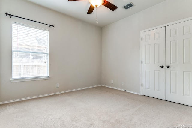 carpeted spare room featuring a wealth of natural light and ceiling fan