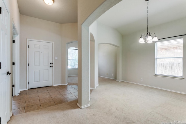 carpeted foyer featuring a chandelier