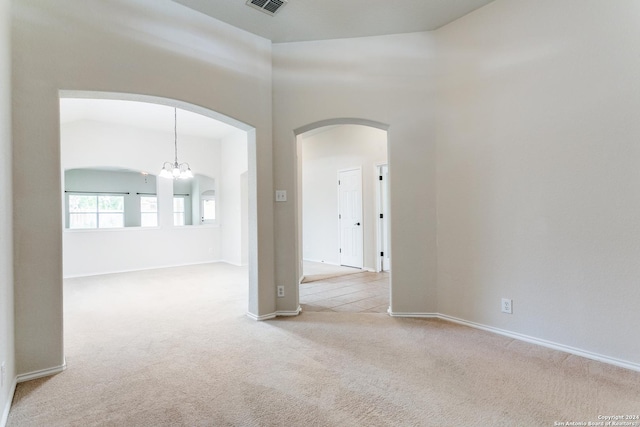 carpeted empty room with a chandelier