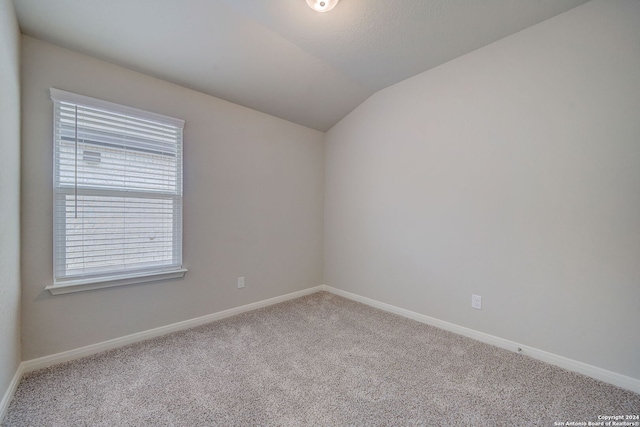 unfurnished room featuring light carpet and lofted ceiling