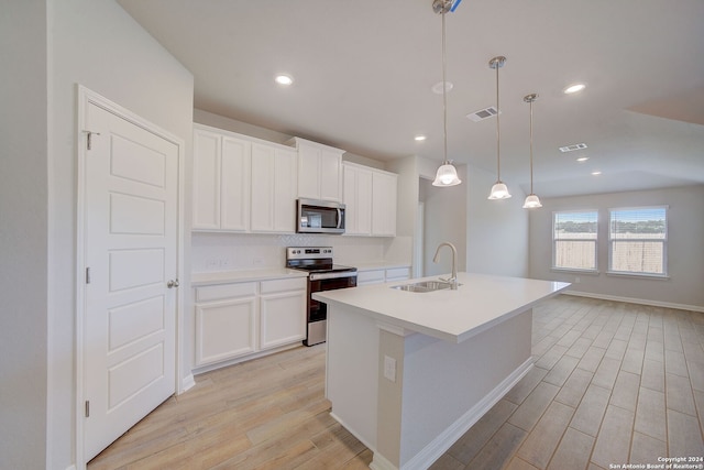 kitchen with an island with sink, appliances with stainless steel finishes, hanging light fixtures, white cabinets, and sink