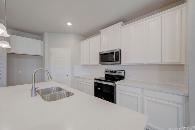 kitchen featuring pendant lighting, appliances with stainless steel finishes, white cabinets, an island with sink, and sink