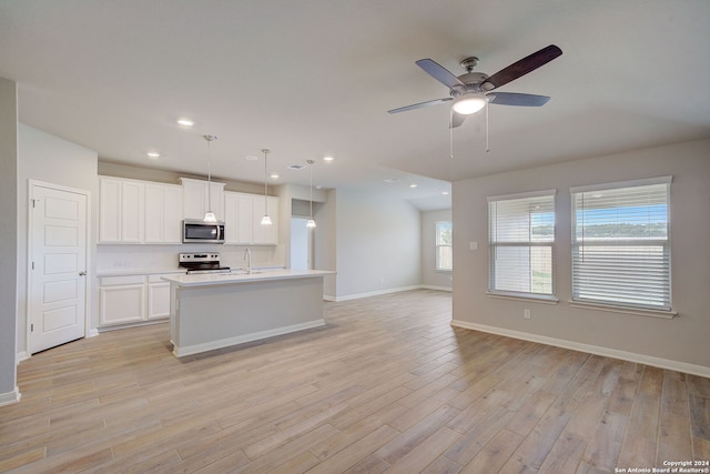 kitchen featuring hanging light fixtures, appliances with stainless steel finishes, white cabinetry, and a center island with sink