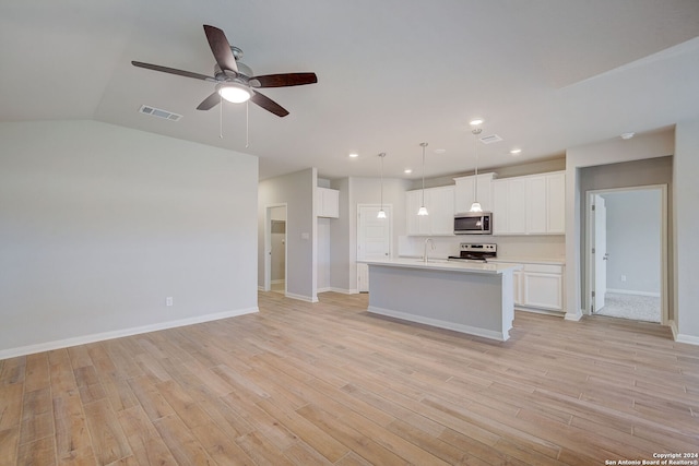 kitchen featuring decorative light fixtures, white cabinets, appliances with stainless steel finishes, and an island with sink