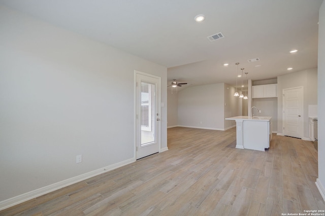 unfurnished living room with ceiling fan, sink, and light hardwood / wood-style floors