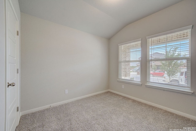 carpeted spare room with vaulted ceiling