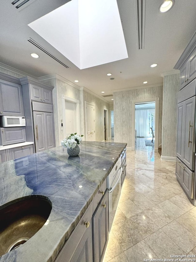 kitchen with ornamental molding, gray cabinets, sink, and dark stone countertops