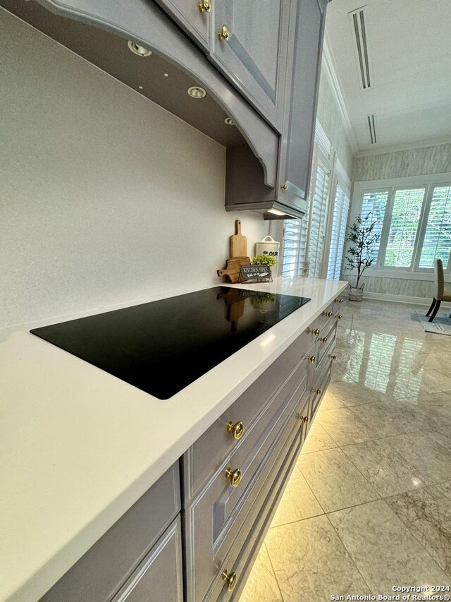 kitchen with ornamental molding, black electric stovetop, and gray cabinetry