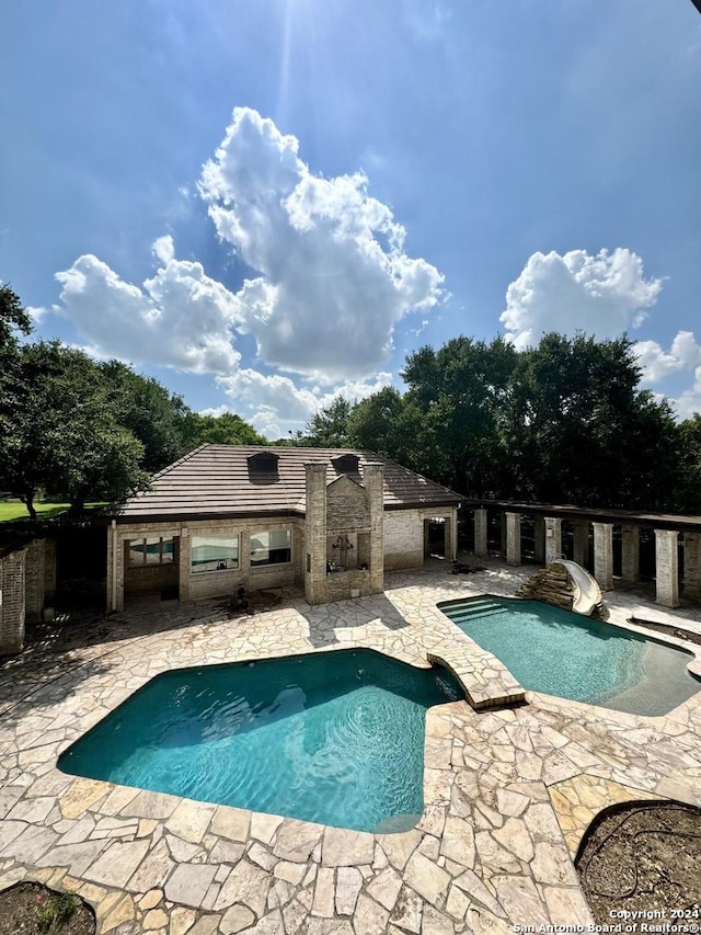 view of pool featuring an outbuilding, a patio area, and a water slide