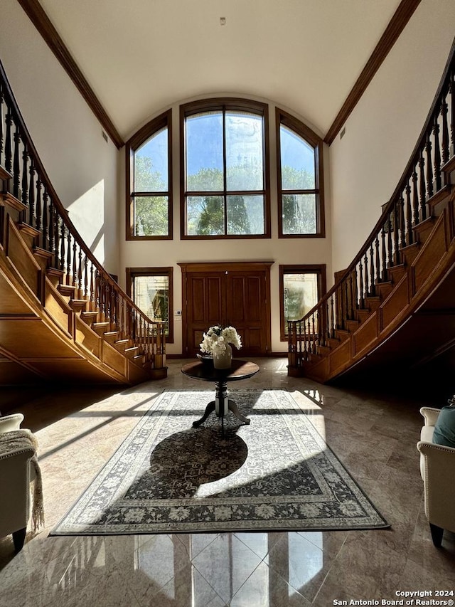 entrance foyer featuring crown molding and high vaulted ceiling