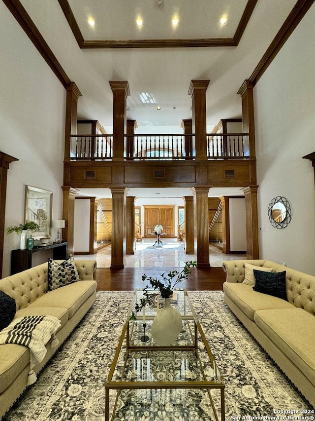 living room featuring ornate columns, crown molding, and a towering ceiling