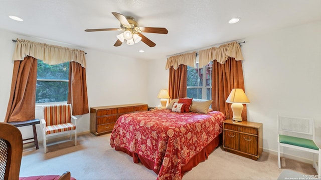 bedroom featuring multiple windows, ceiling fan, and light colored carpet