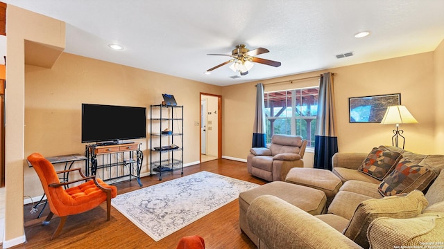 living room featuring ceiling fan and dark hardwood / wood-style flooring