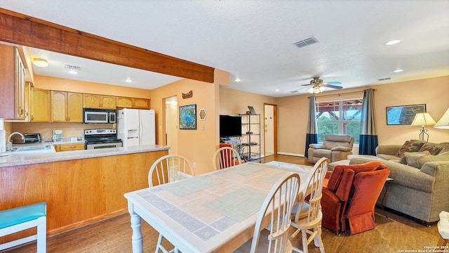 dining area featuring beamed ceiling, light hardwood / wood-style floors, ceiling fan, and sink