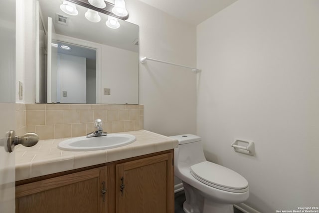 bathroom featuring decorative backsplash, toilet, and vanity