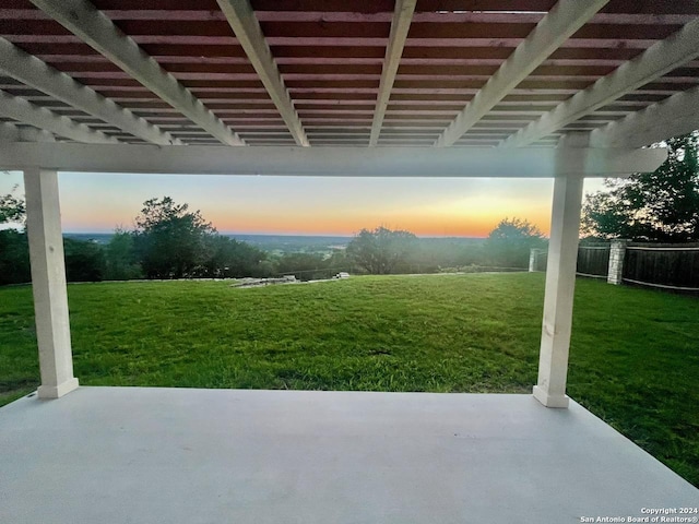 patio terrace at dusk featuring a lawn