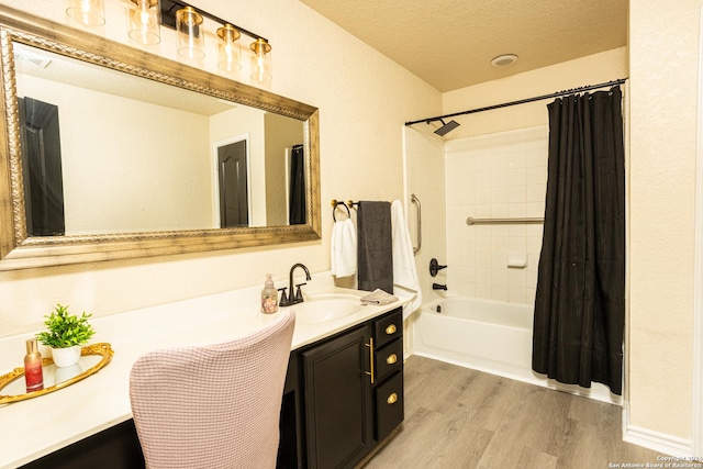 bathroom with vanity, hardwood / wood-style floors, shower / bath combo with shower curtain, and a textured ceiling