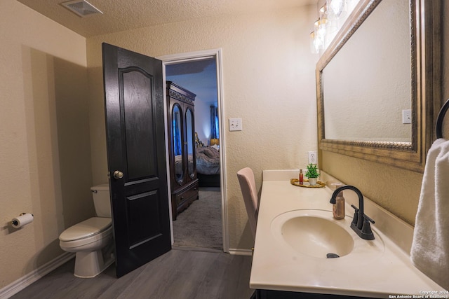 bathroom featuring wood-type flooring, vanity, a textured ceiling, and toilet