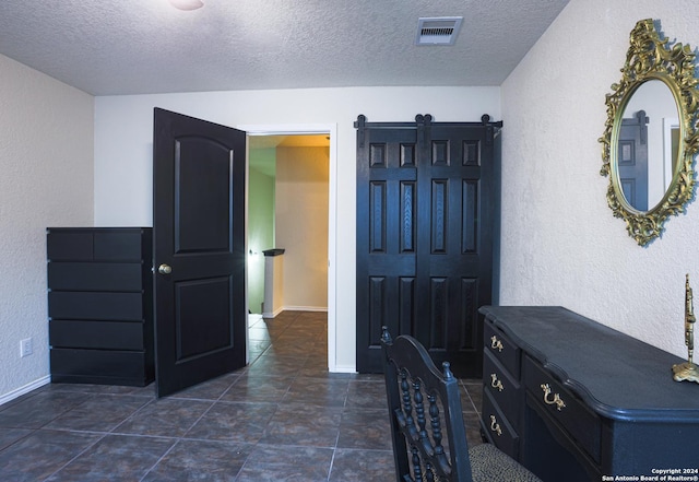 interior space with a barn door and a textured ceiling