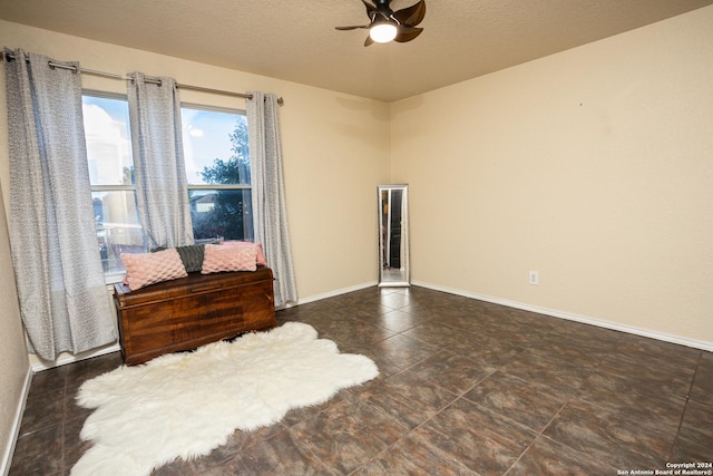 unfurnished room with ceiling fan and a textured ceiling