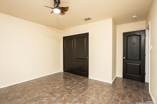 unfurnished room with ceiling fan and a textured ceiling