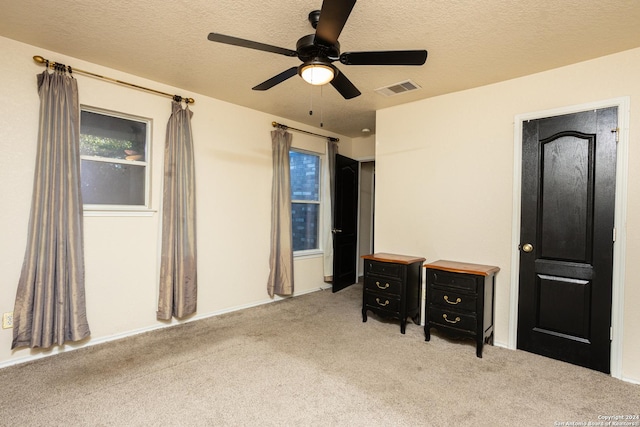 bedroom featuring ceiling fan, light colored carpet, and a textured ceiling